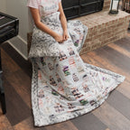 Person sitting on a fireplace with a book patterned blanket draped over them in a home setting.