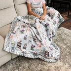 Person sitting on a couch with a blanket featuring book patterns