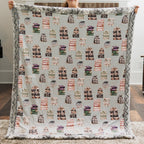 Person holding a blanket with book pattern in a room.