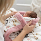 Person holding a baby wrapped in a pink blanket with a floral pattern