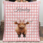 Person holding a pink checkered blanket with a cow illustration and 'Kensley' text.