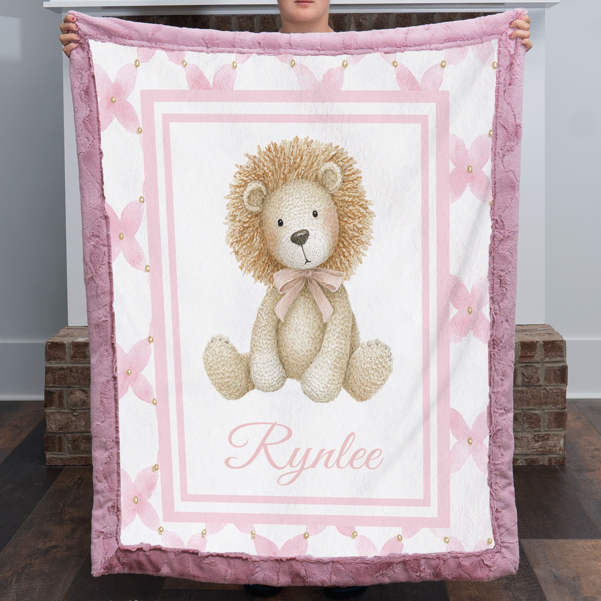 Personalized lion baby blanket with mauve fur trim, pink floral border, held by fireplace mantel