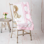 Personalized lion minky baby blanket with pink rosette fur trim, draped on rustic chair with roses