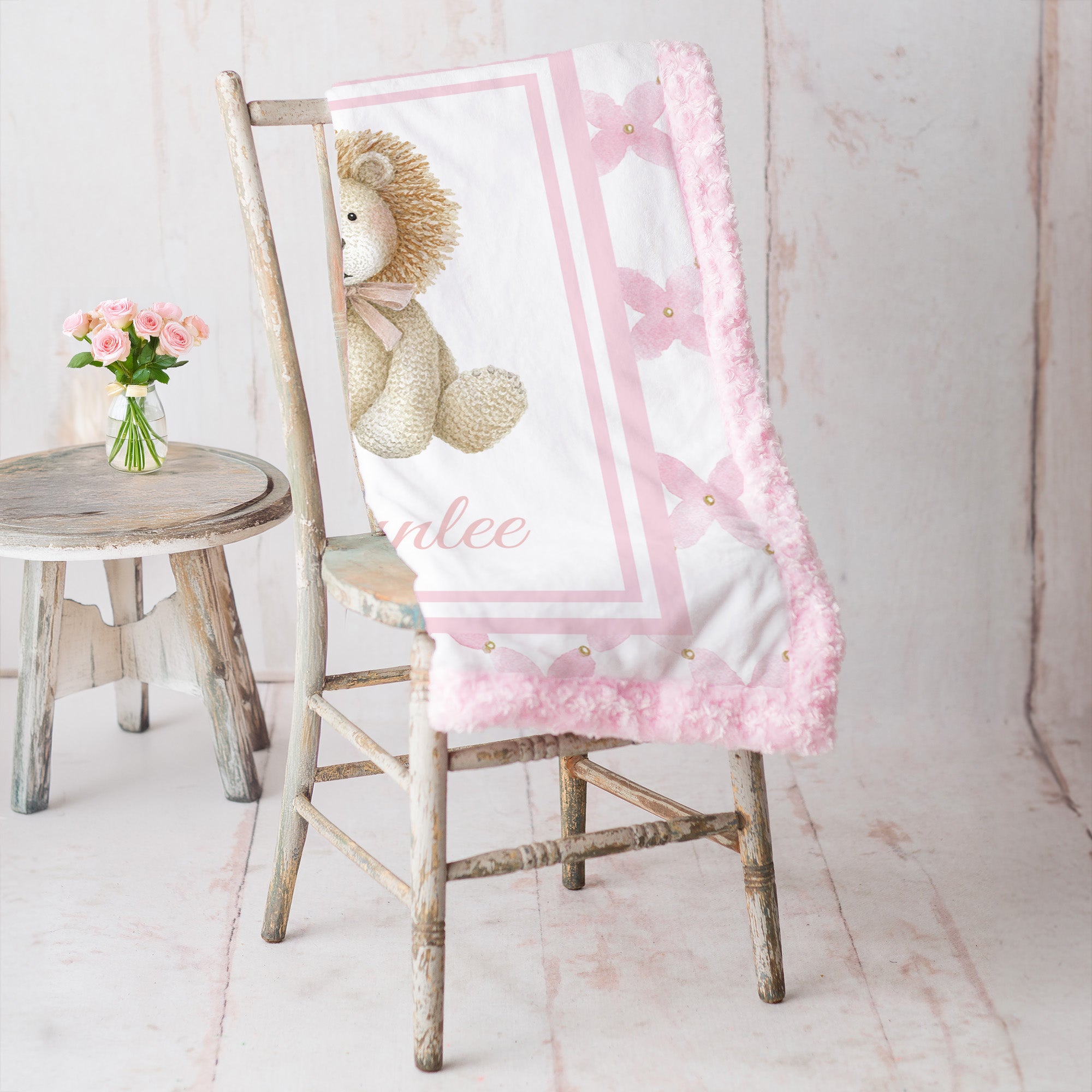 Personalized lion minky baby blanket with pink rosette fur trim, draped on rustic chair with roses
