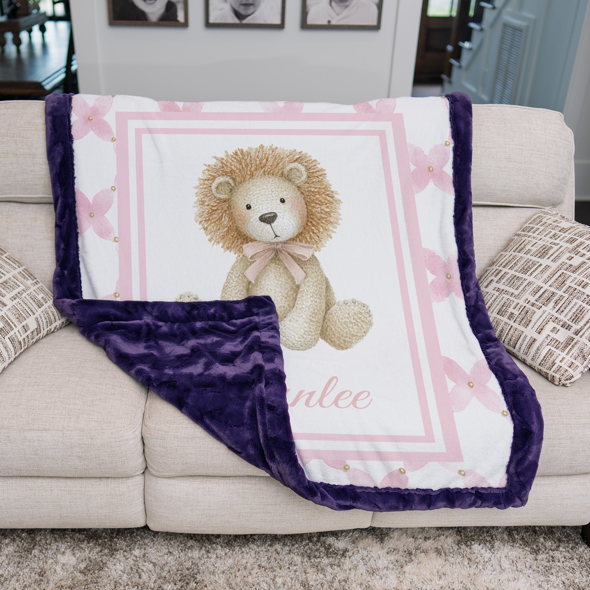 Personalized lion minky baby blanket with plum fur trim, draped over cream couch cushions