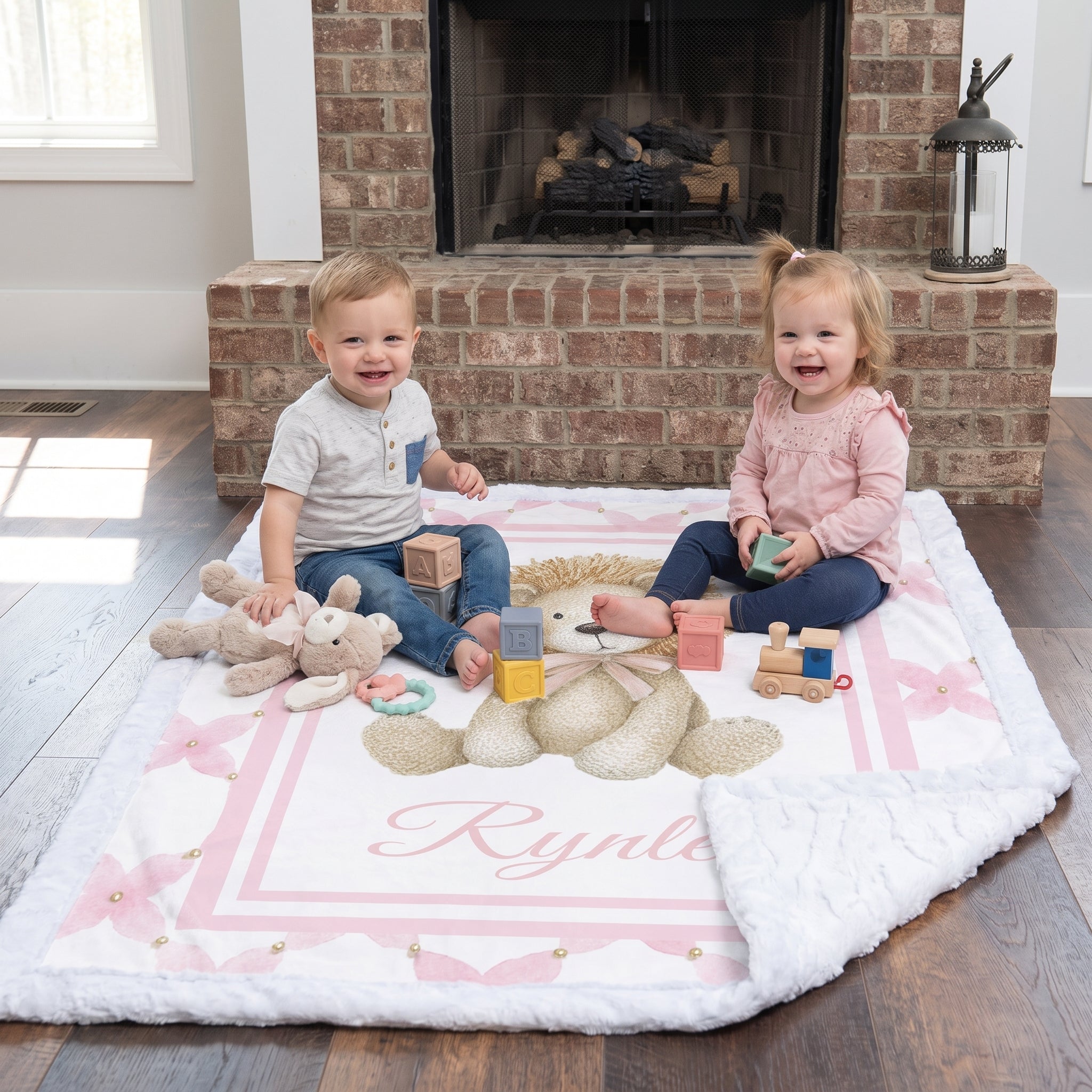 Two toddlers playing with blocks on personalized lion minky baby blanket by brick fireplace
