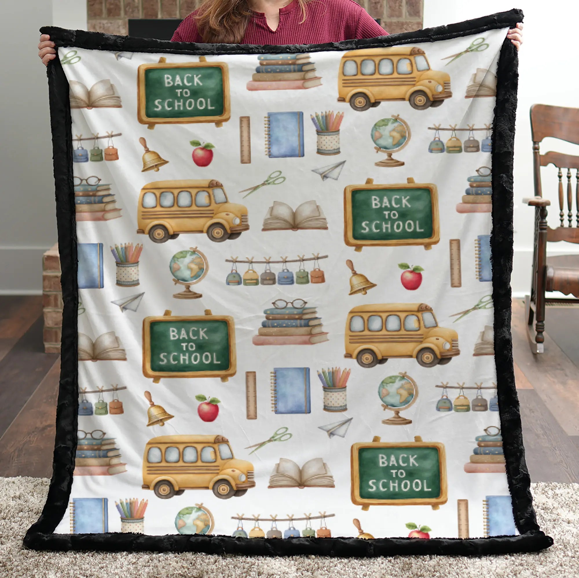 Blanket with 'Back to School' pattern featuring school buses, books, and chalkboards held by a person.