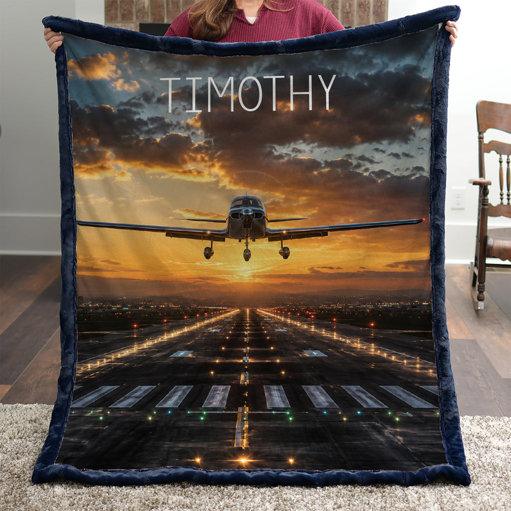 Personalized airplane photo blanket with navy faux fur border, held by woman near brick fireplace