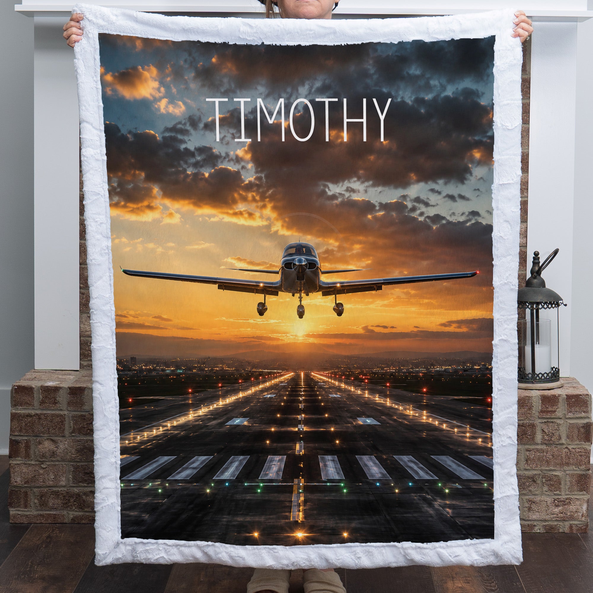 Personalized airplane photo blanket with white faux fur border, held by woman near brick pillar