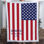 Personalized American flag minky blanket with family name held up near brick fireplace mantel