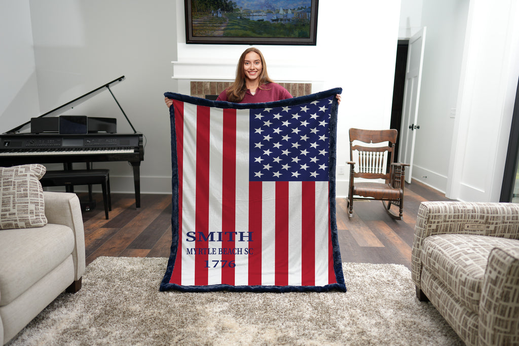 Woman holding personalized American flag minky blanket with navy trim in living room