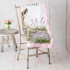 Personalized baby donkey minky blanket with pink trim draped over vintage chair beside pink roses