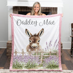Woman holding personalized baby donkey minky blanket with pink trim over fireplace mantel