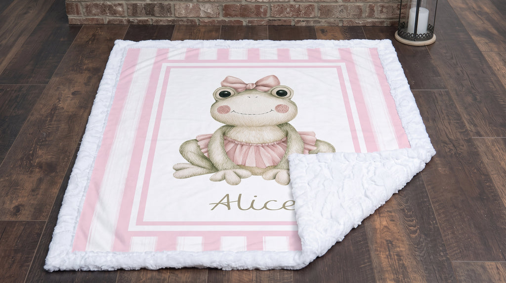 Personalized minky ballerina frog baby blanket flat-lay on wood floor by fireplace