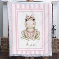Personalized minky ballerina frog baby blanket with pink stripe border held up by fireplace