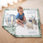 Baby sitting on personalized hot air balloon milestone blanket with sage trim and toys