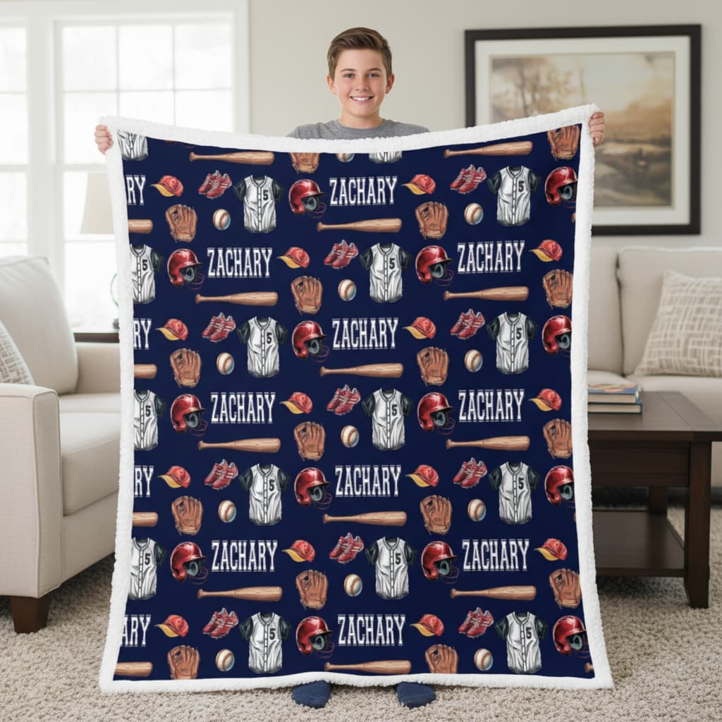 Person holding a blanket with baseball-themed patterns and the name 'Zachary' printed repeatedly.