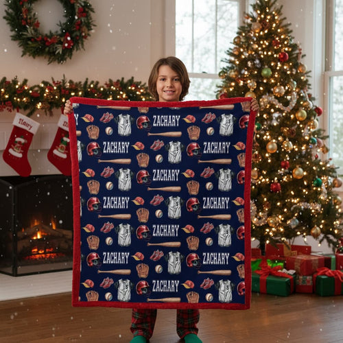 Child holding a personalized blanket with sports-themed patterns and 'ZACHARY' printed multiple times, in a festive room with Christmas decorations.