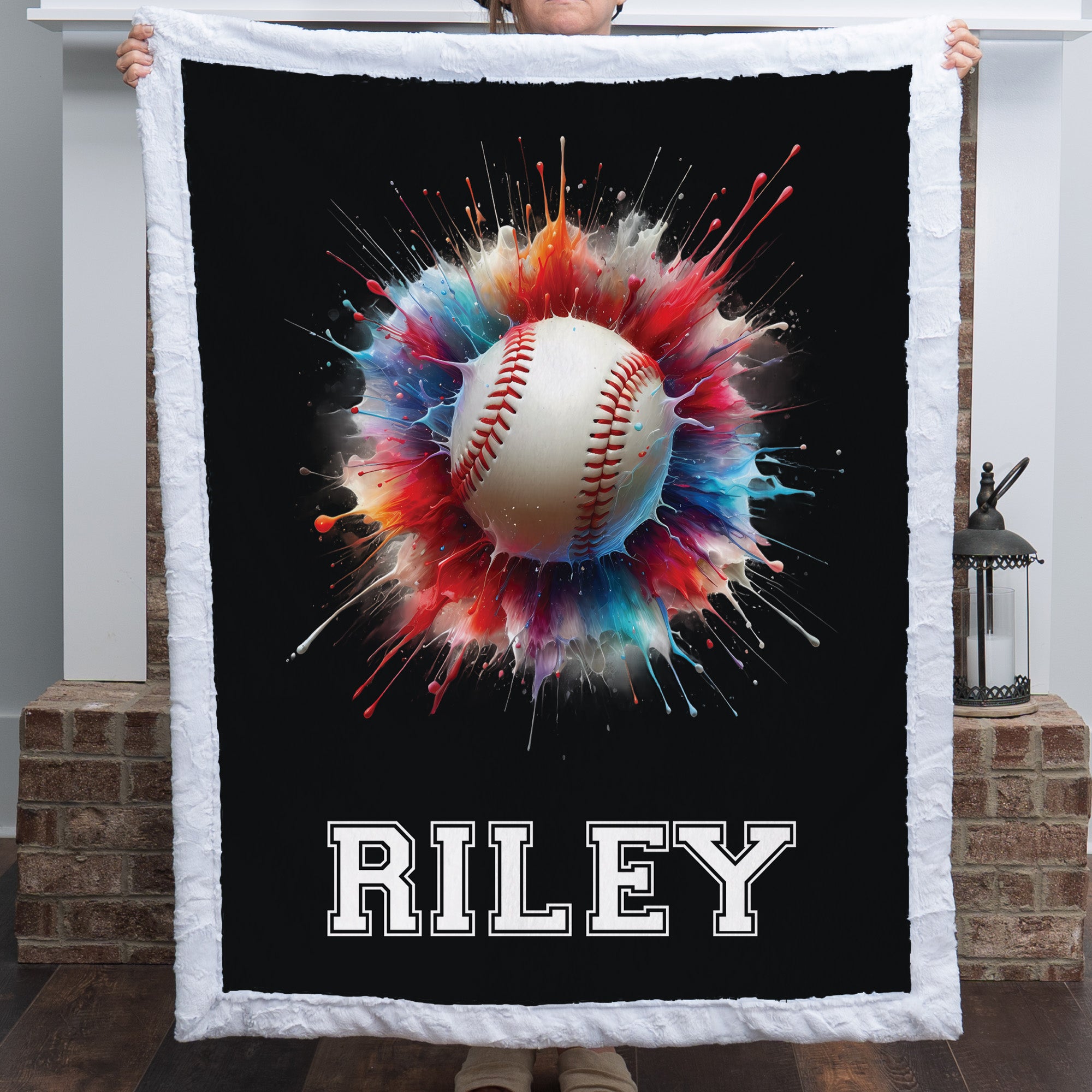 Personalized baseball minky blanket with white sherpa trim and custom name, by a brick fireplace