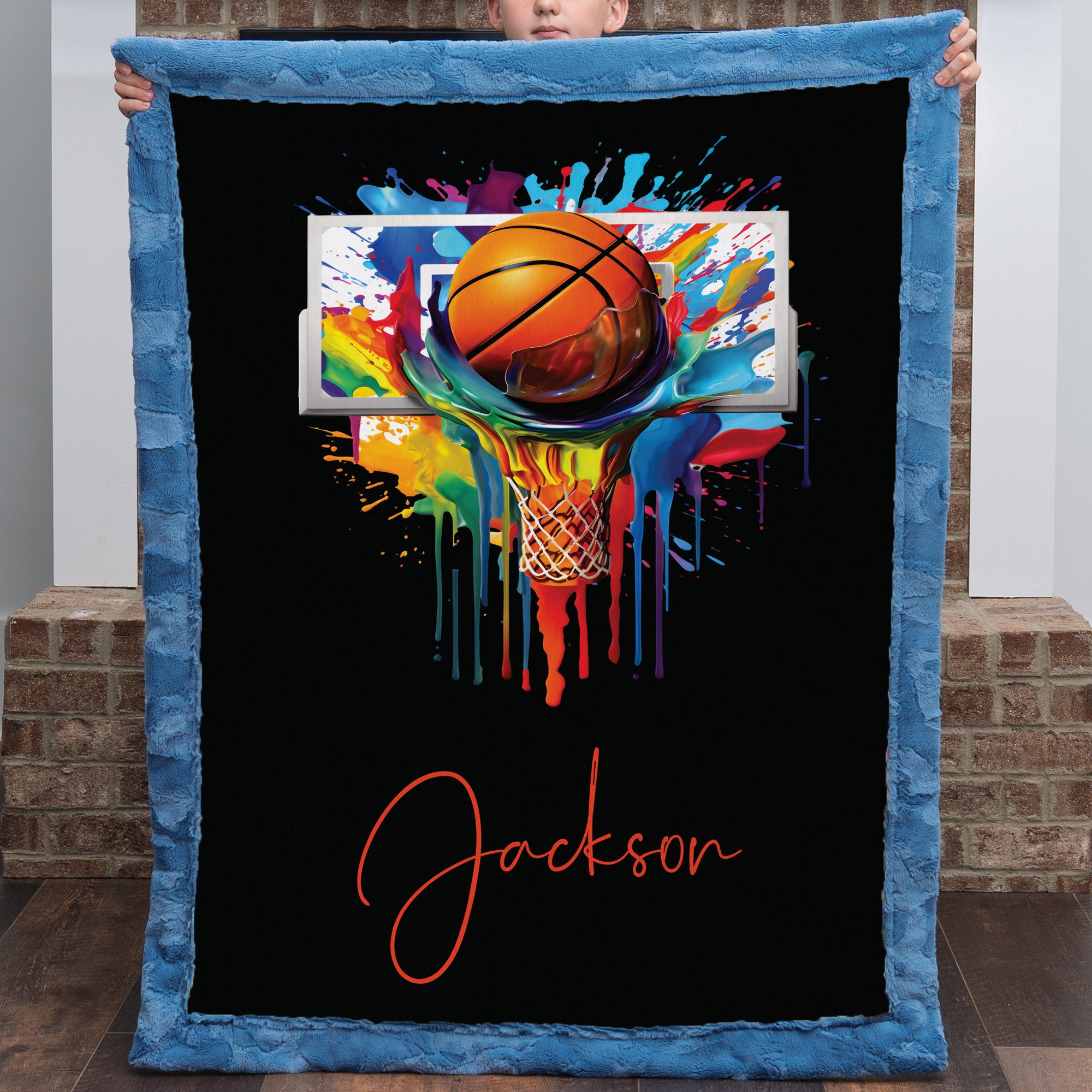 Personalized basketball Luxe Cuddle blanket held up, black background with colorful hoop art and name in script