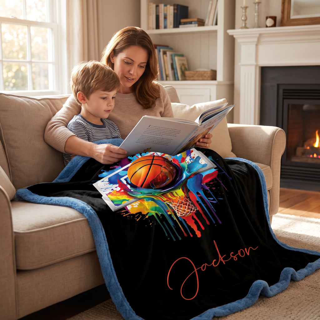 Mom reading to young boy on couch, both covered by personalized basketball Luxe Cuddle blanket by fireplace