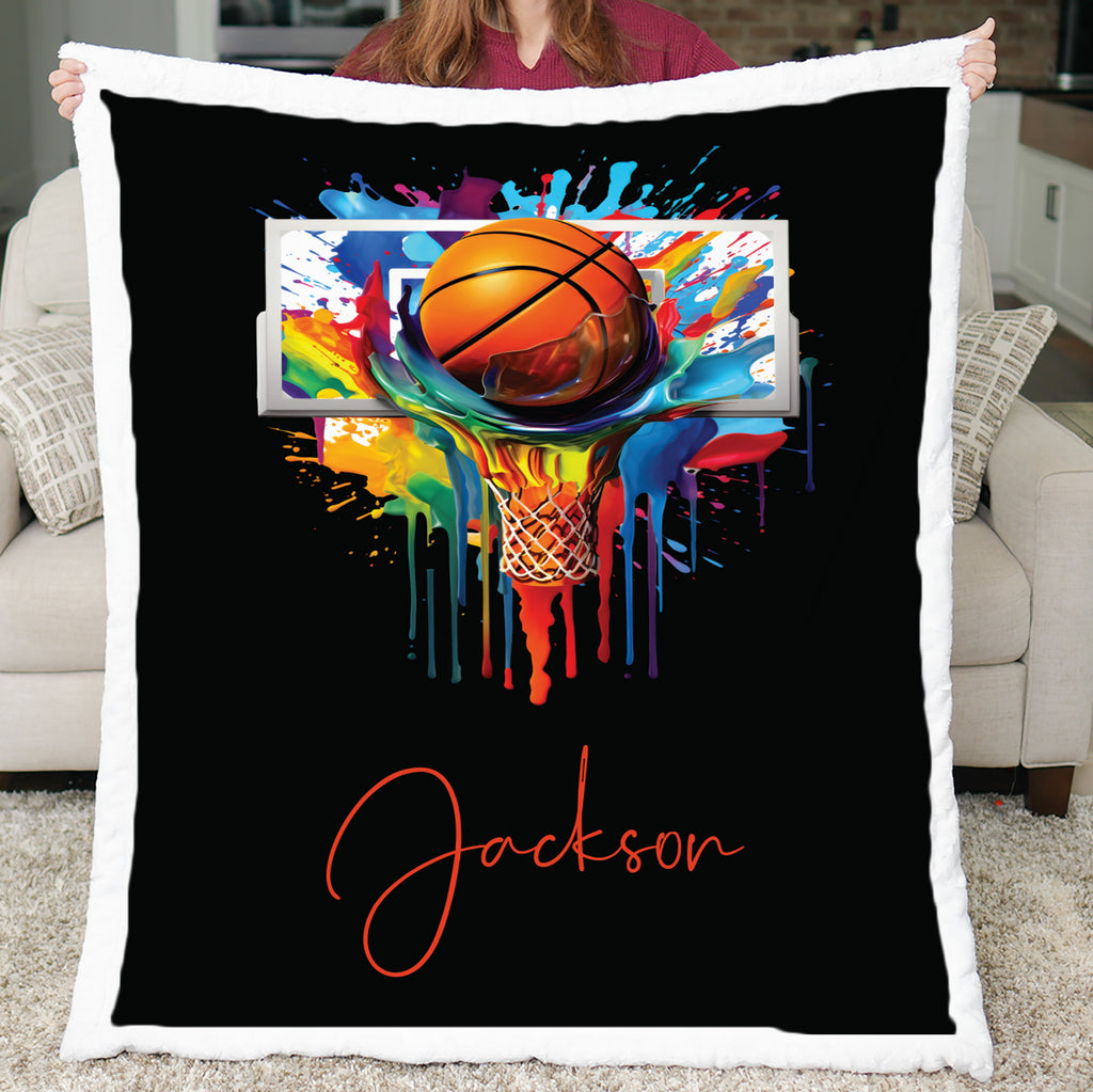 Personalized basketball blanket with white Luxe Cuddle border held up, colorful hoop art on black background