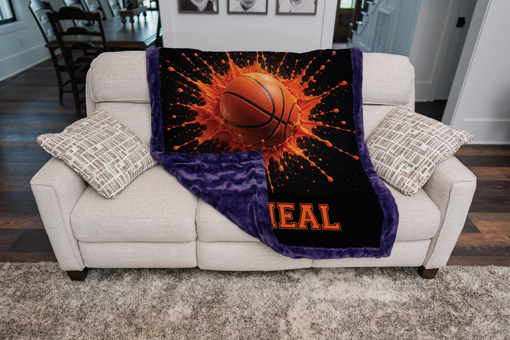 Personalized basketball minky blanket with purple minky back, folded over a couch