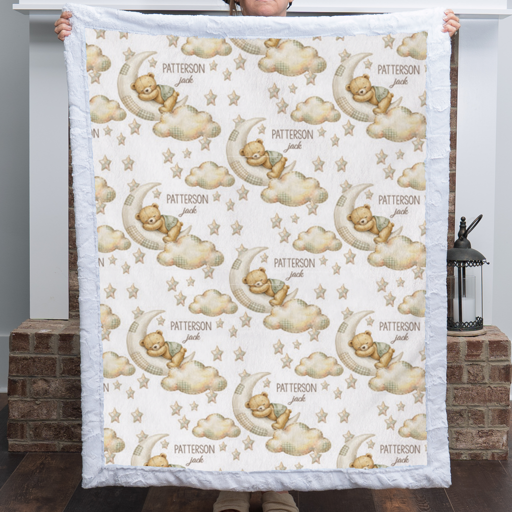 Woman holding personalized bear and moon baby blanket with white minky trim by fireplace