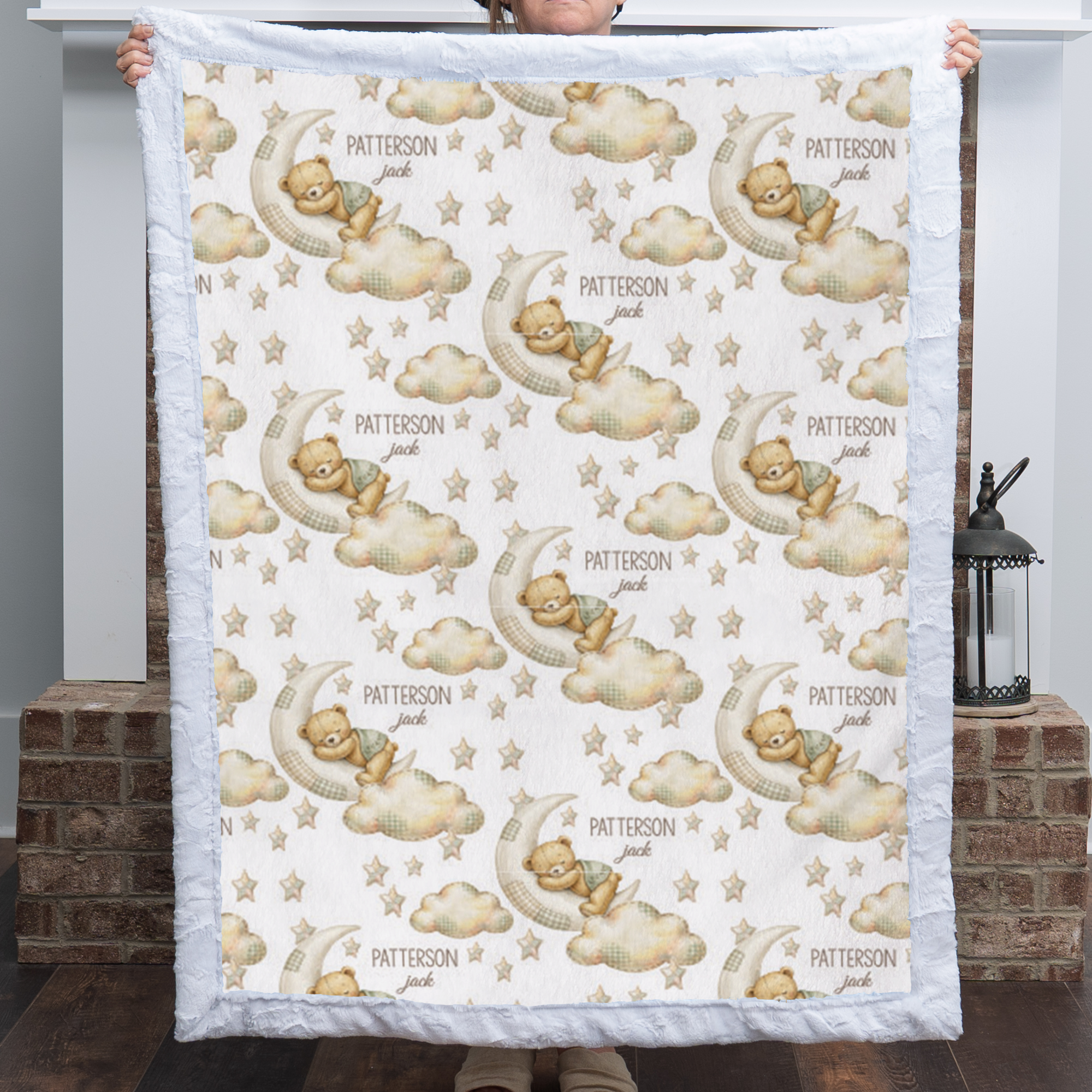 Woman holding personalized bear and moon baby blanket with white minky trim by fireplace