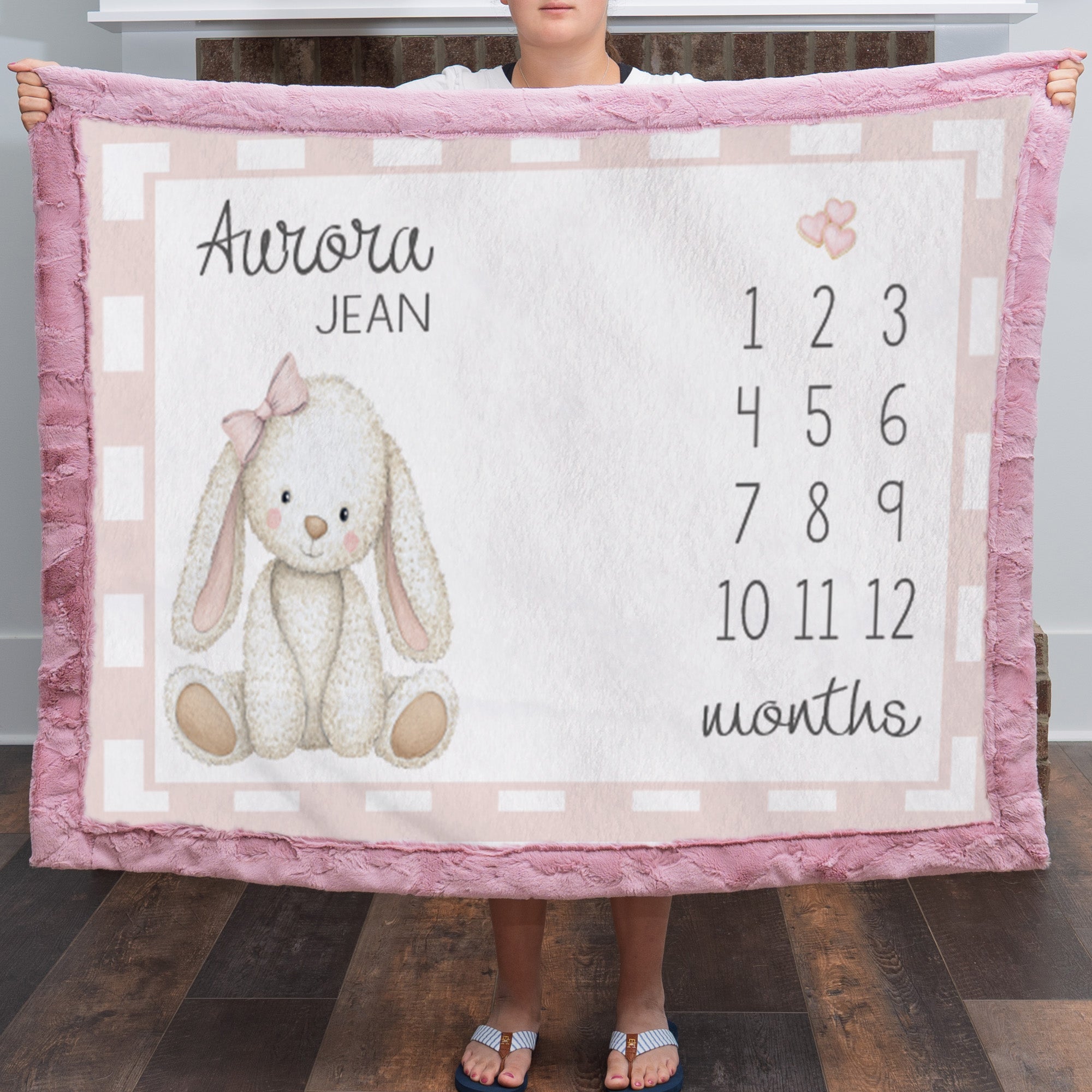 Woman holding personalized bunny milestone blanket with custom name, pink faux fur trim