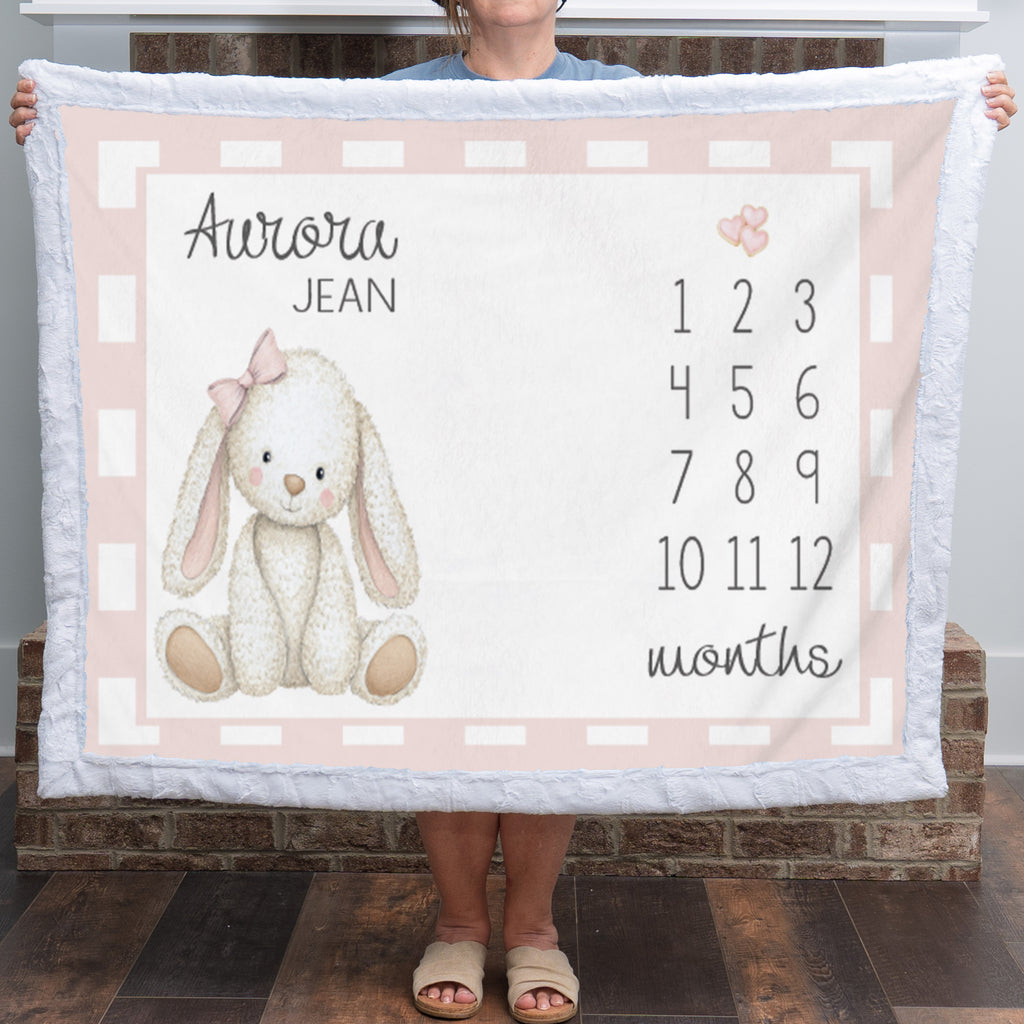 Woman holding personalized bunny milestone blanket with custom name, white faux fur trim