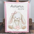 Woman holding personalized bunny minky baby blanket with pink rosette border by fireplace