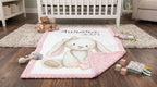 Personalized bunny minky baby blanket laid flat on nursery rug with folded pink minky corner