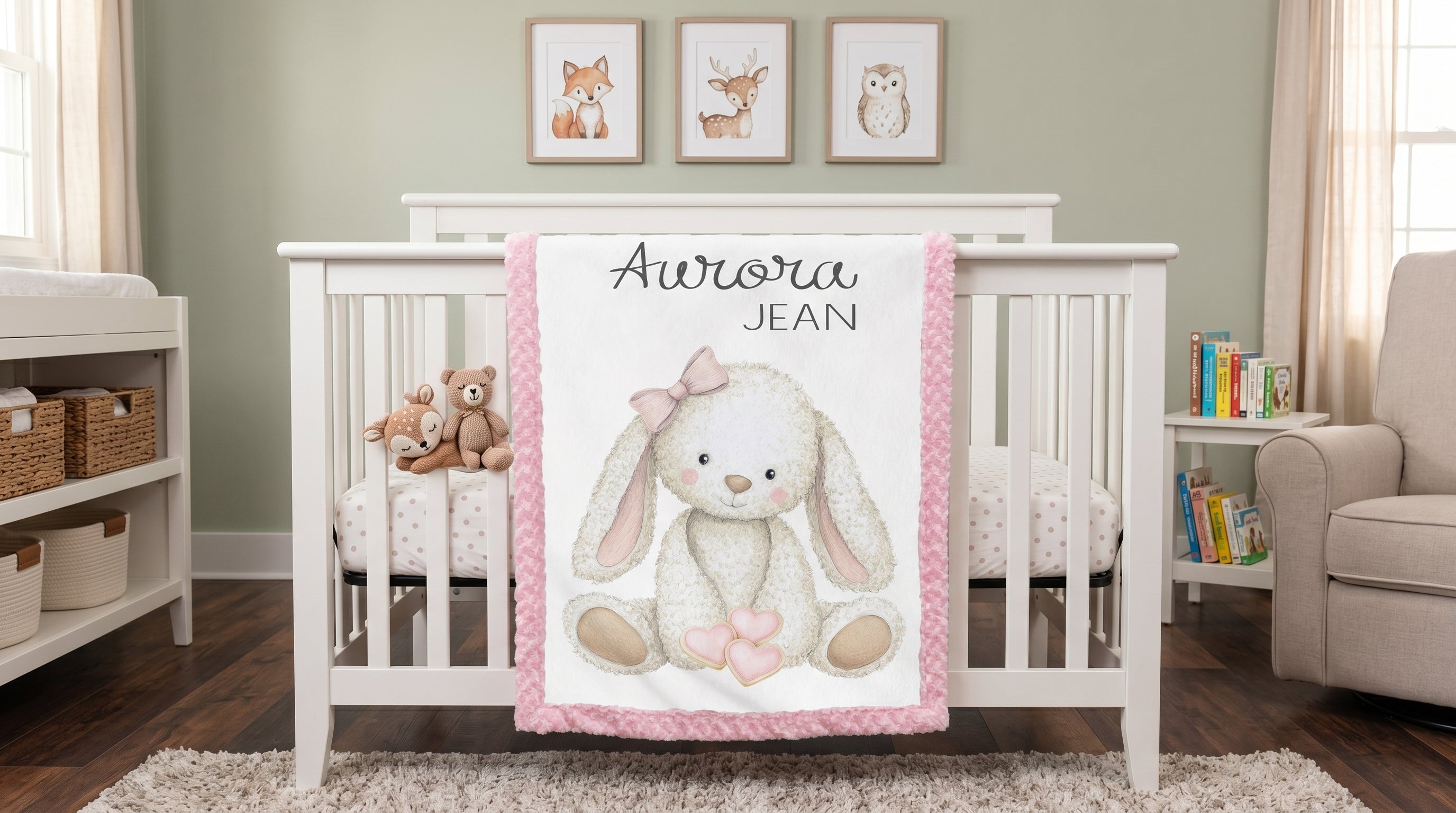 Personalized bunny minky baby blanket with Aurora Jean name, draped over white nursery crib rail