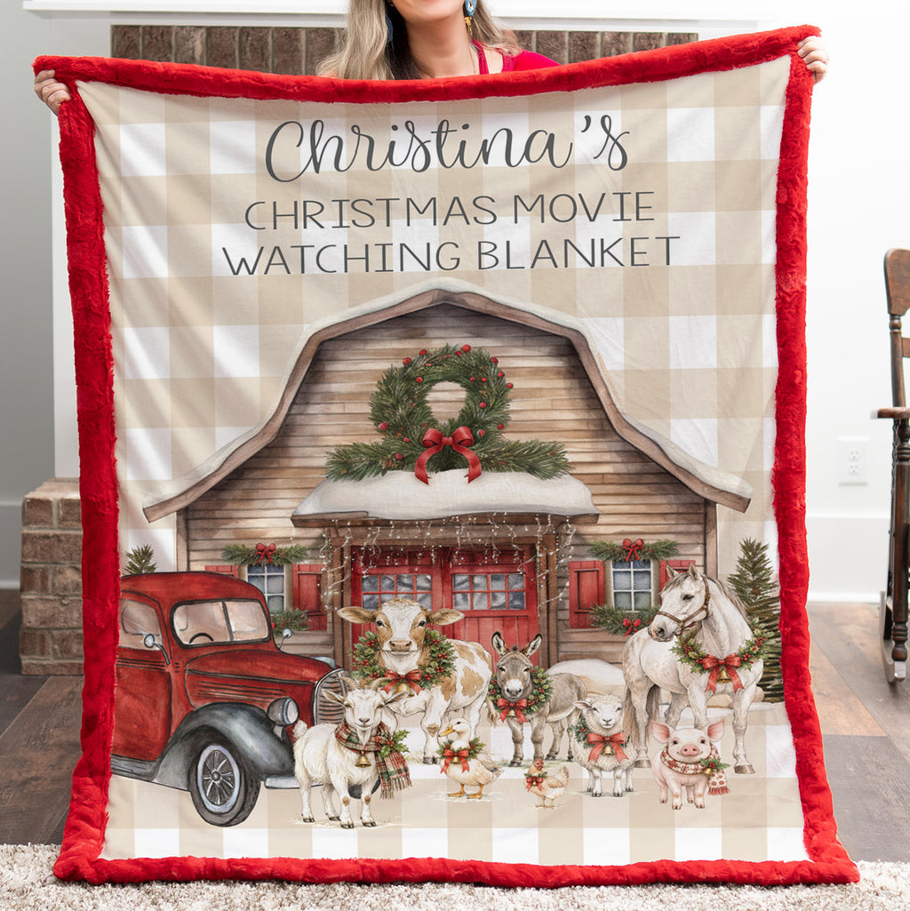 Woman holding personalized Christmas farmhouse minky blanket with red trim indoors