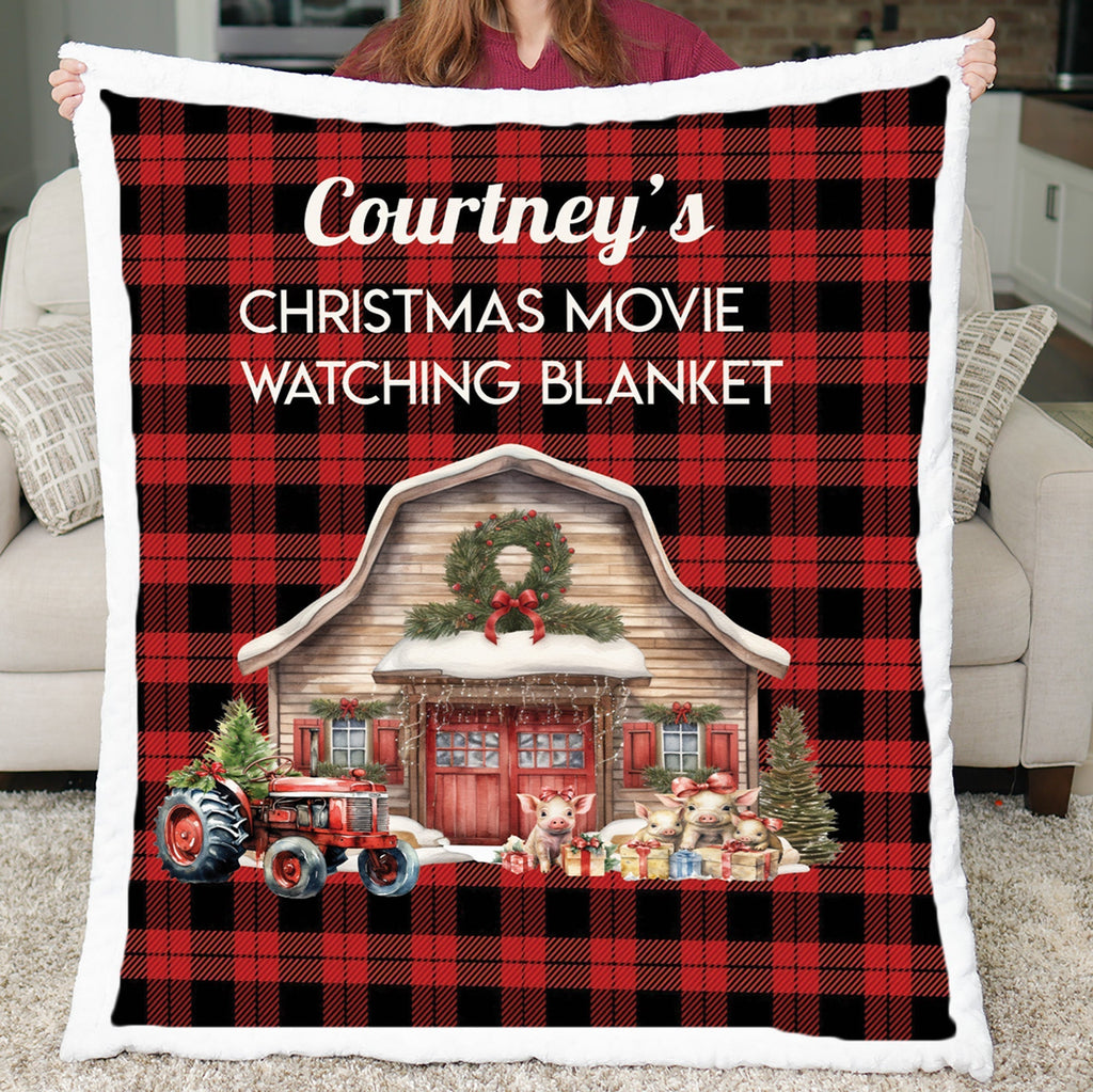 Personalized red buffalo plaid Christmas movie watching blanket held up, showing farm barn scene with faux fur border