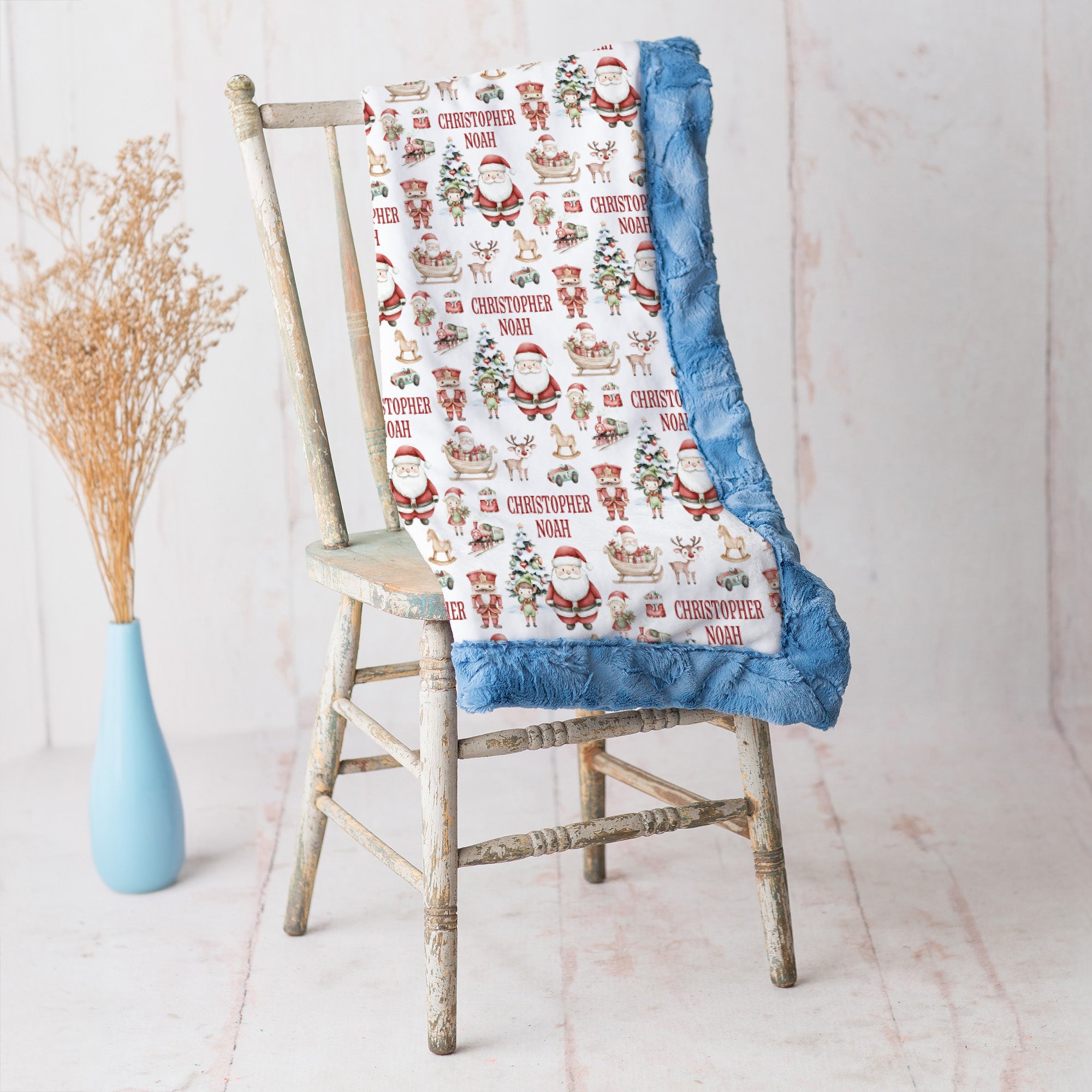 Personalized Christmas minky blanket with Santa print and blue trim draped on vintage chair