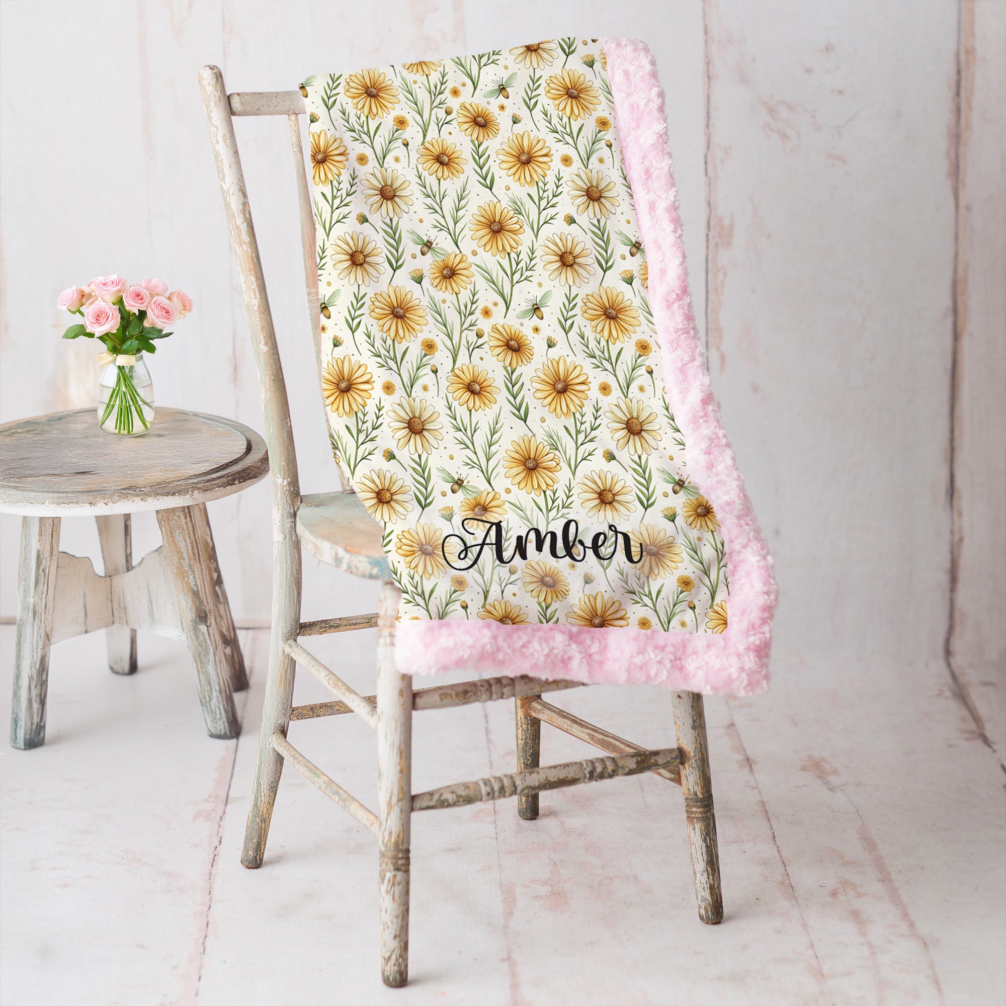Pink trim minky blanket with daisy floral print and personalized name, draped over vintage chair