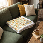 White trim minky blanket with daisy floral print and personalized name, folded on a couch