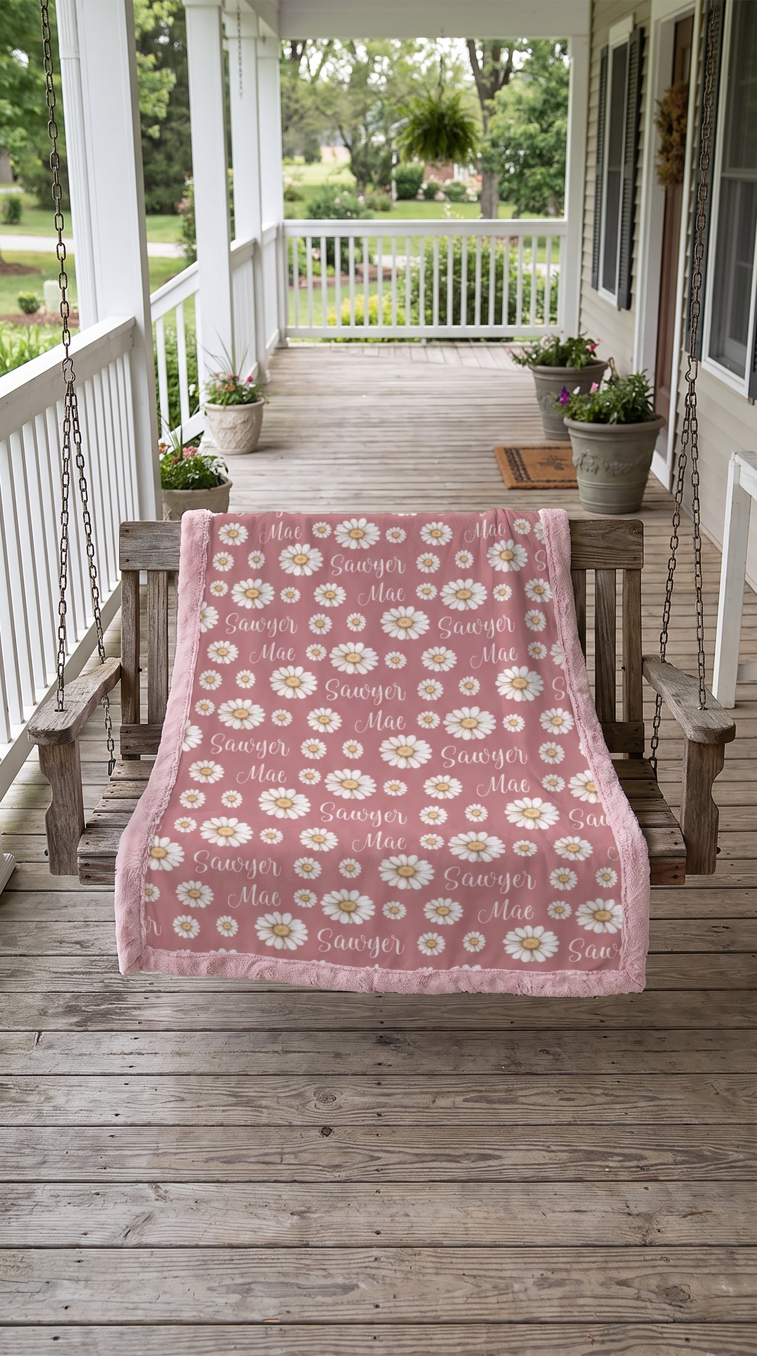 Personalized daisy minky blanket with pink trim draped over porch swing