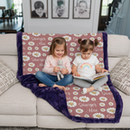 Two girls sitting on personalized daisy minky blanket with purple trim on couch