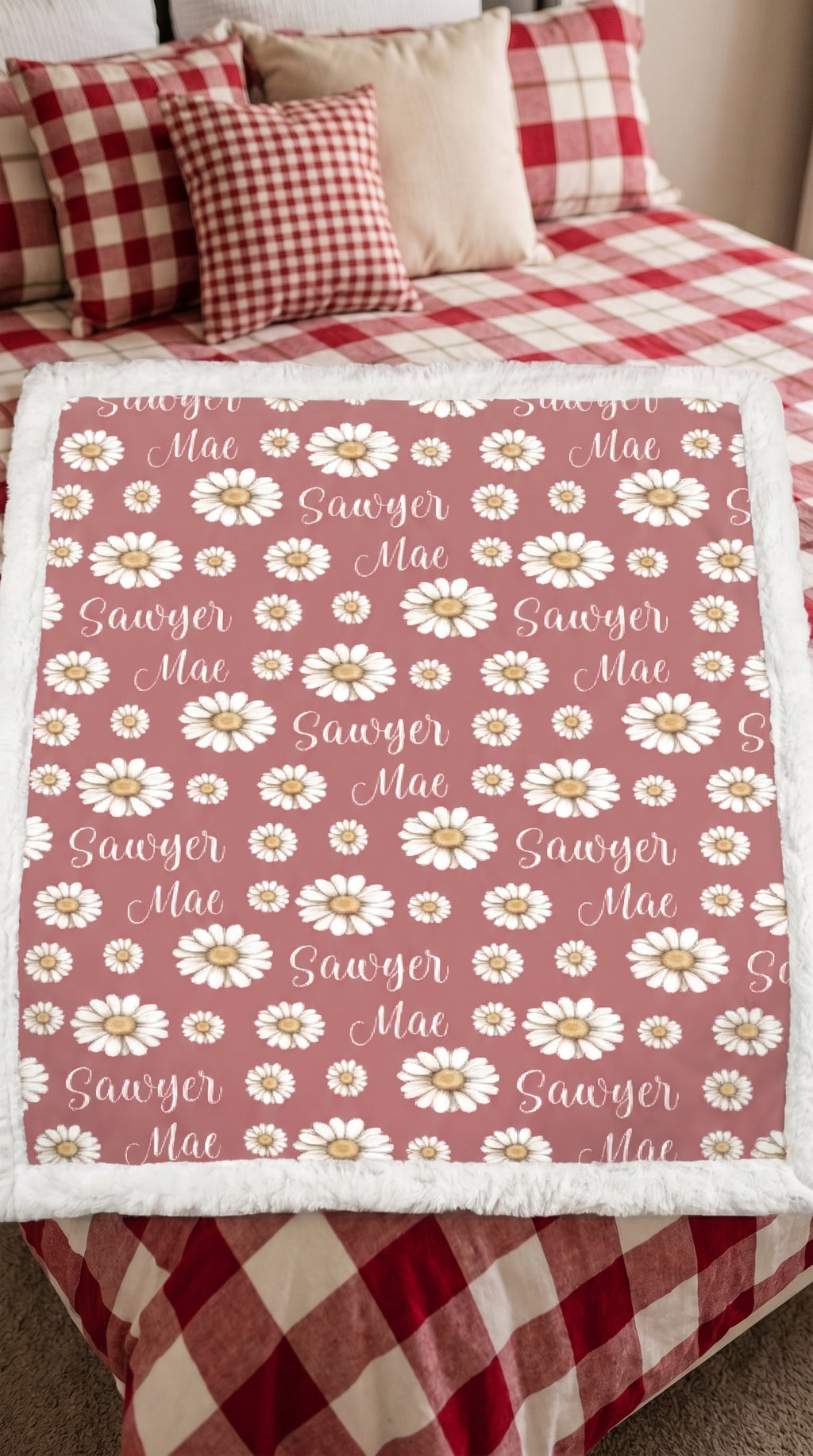 Personalized daisy minky blanket with white sherpa back draped over plaid bed
