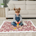 Toddler girl sitting on personalized daisy minky blanket with white trim playing with blocks