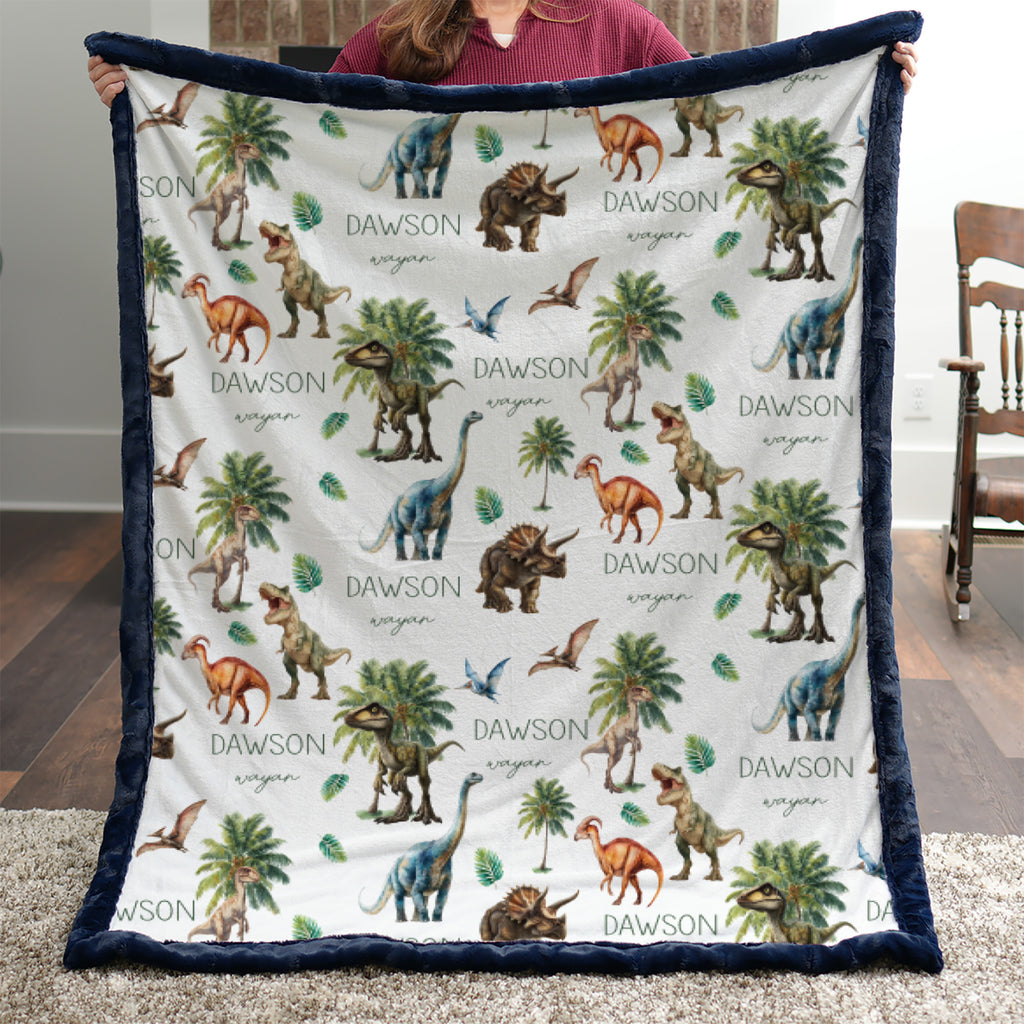 Personalized dinosaur minky baby blanket with navy trim and custom name, held by a woman