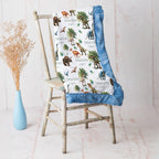 Close-up of personalized dinosaur minky blanket draped over vintage chair with blue trim