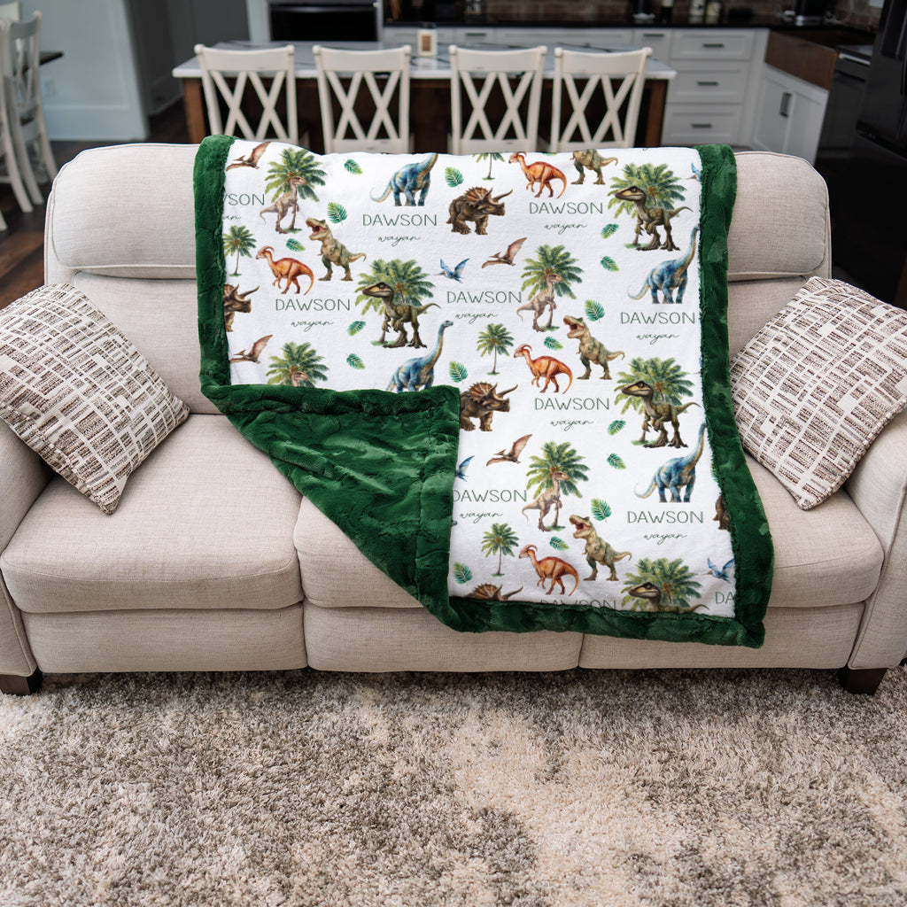 Personalized dinosaur minky blanket with green minky back, folded over a couch