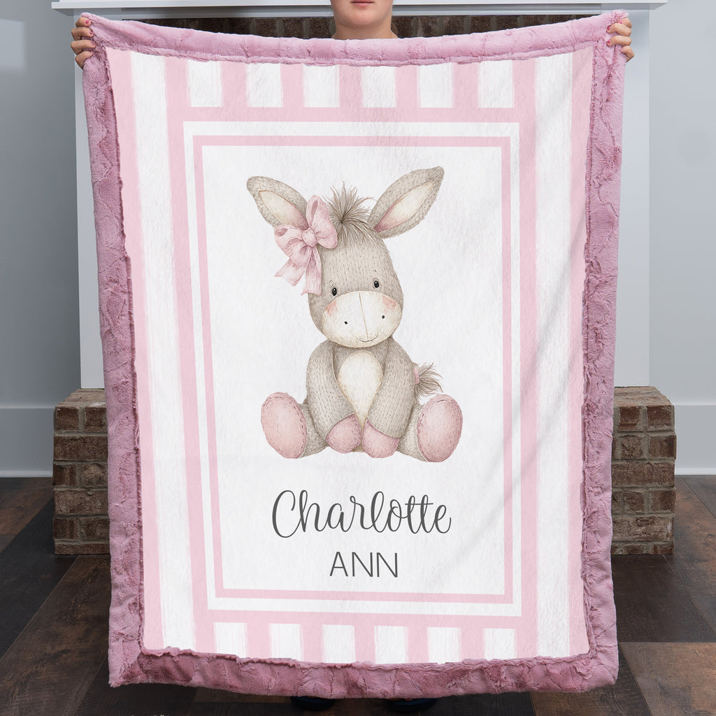 Personalized minky donkey baby blanket with mauve pink fur border by fireplace