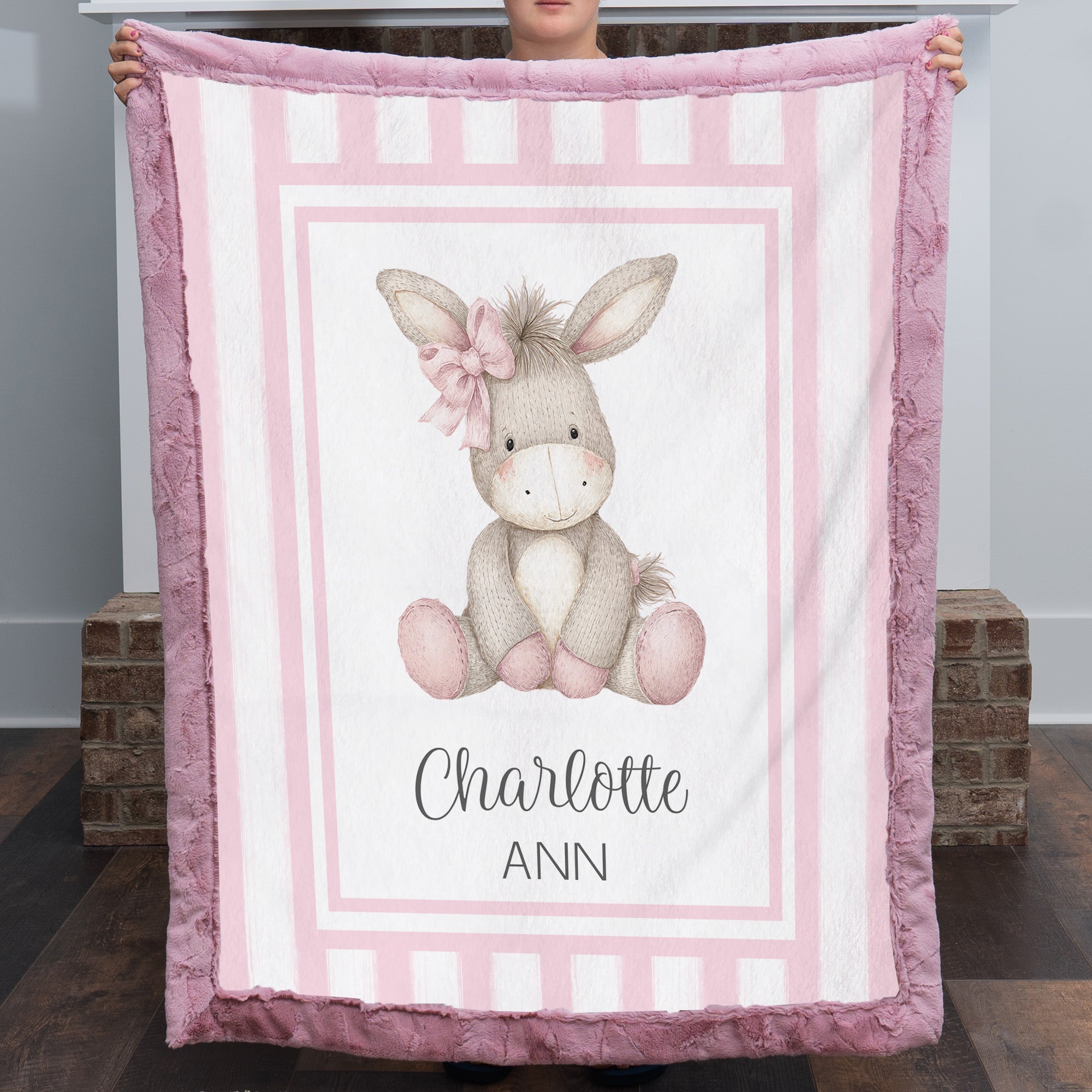 Personalized minky donkey baby blanket with mauve pink fur border by fireplace