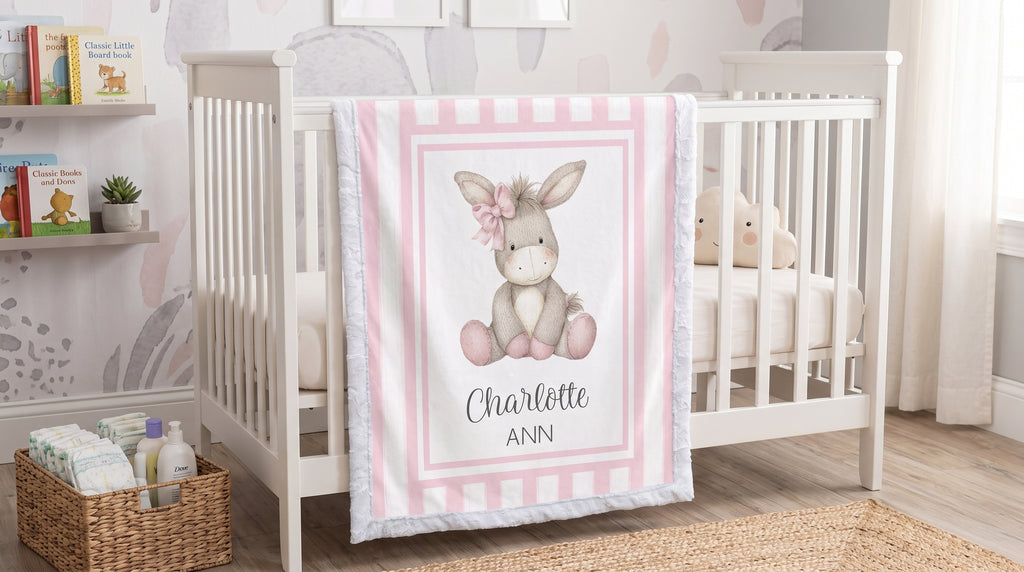 Personalized minky donkey baby blanket with pink stripe border draped over crib