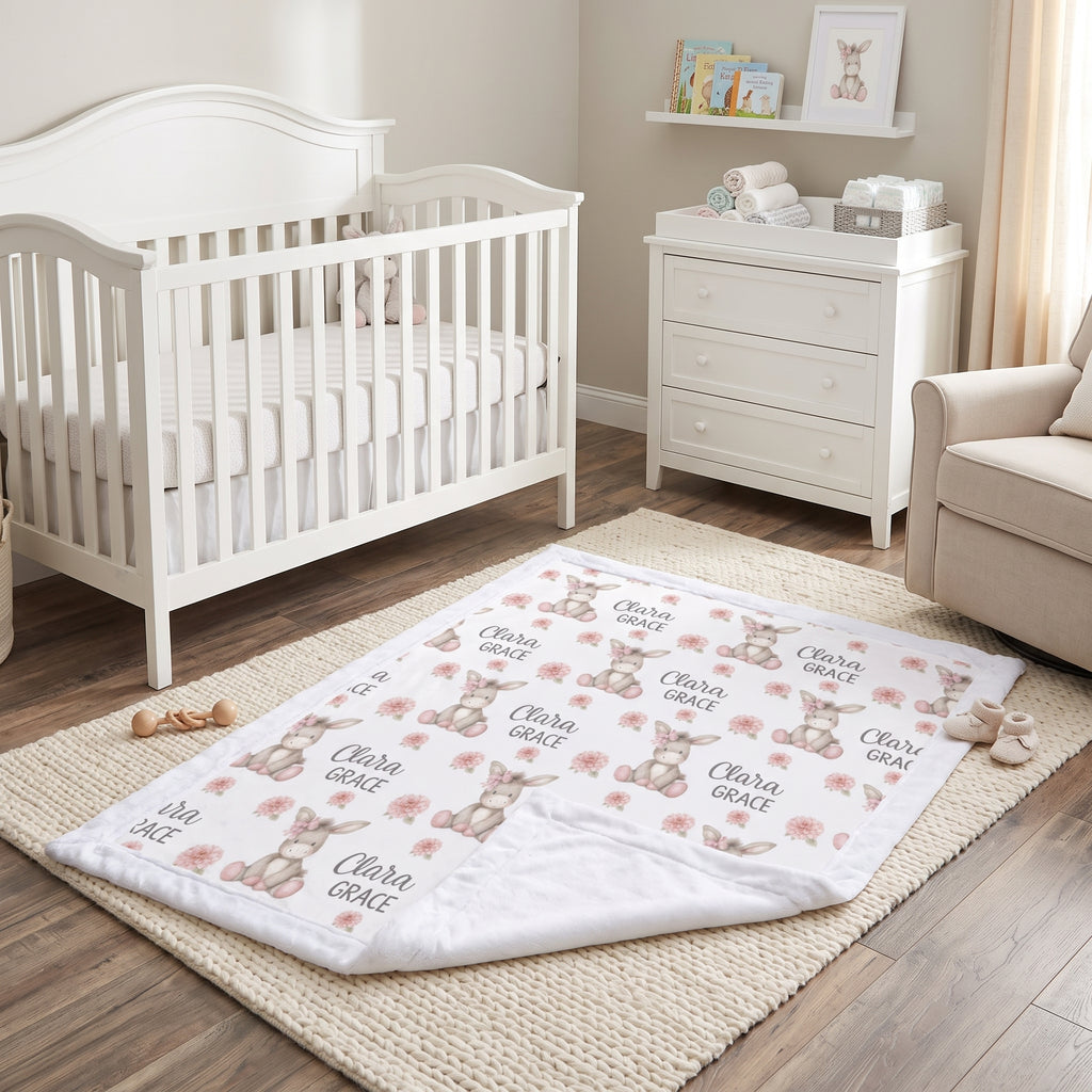 Personalized minky donkey baby blanket with white fur border on rug beside nursery crib
